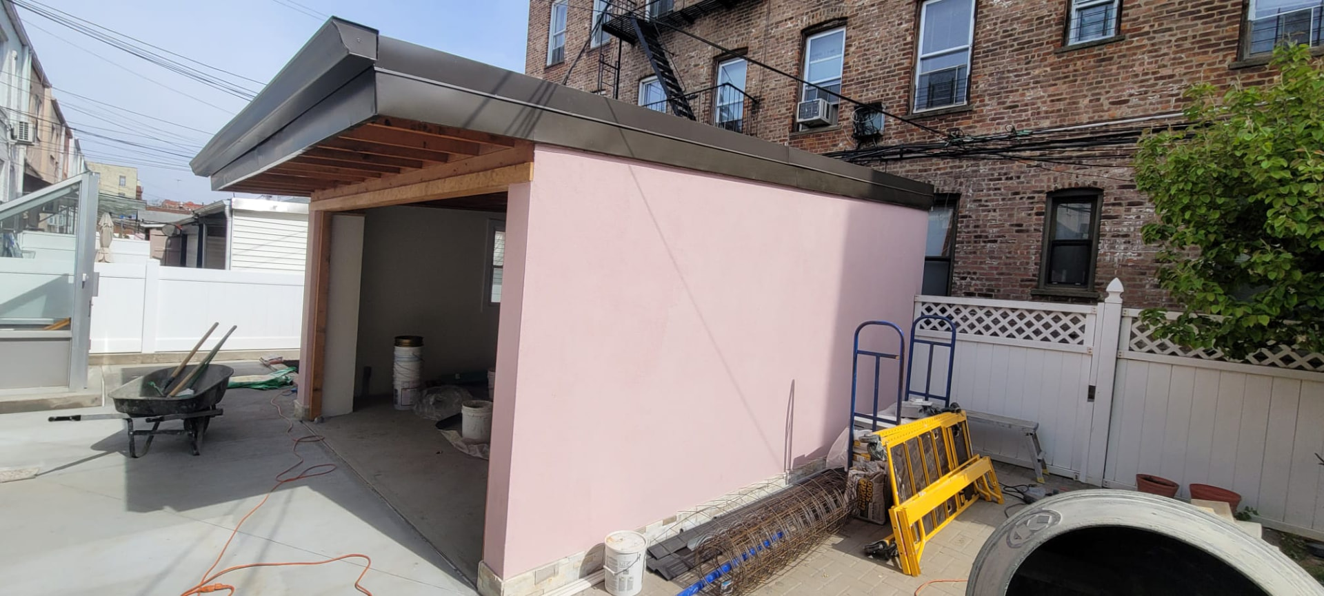 Completed backyard garage with a metal roof, finished pink exterior walls and a clean concrete yard