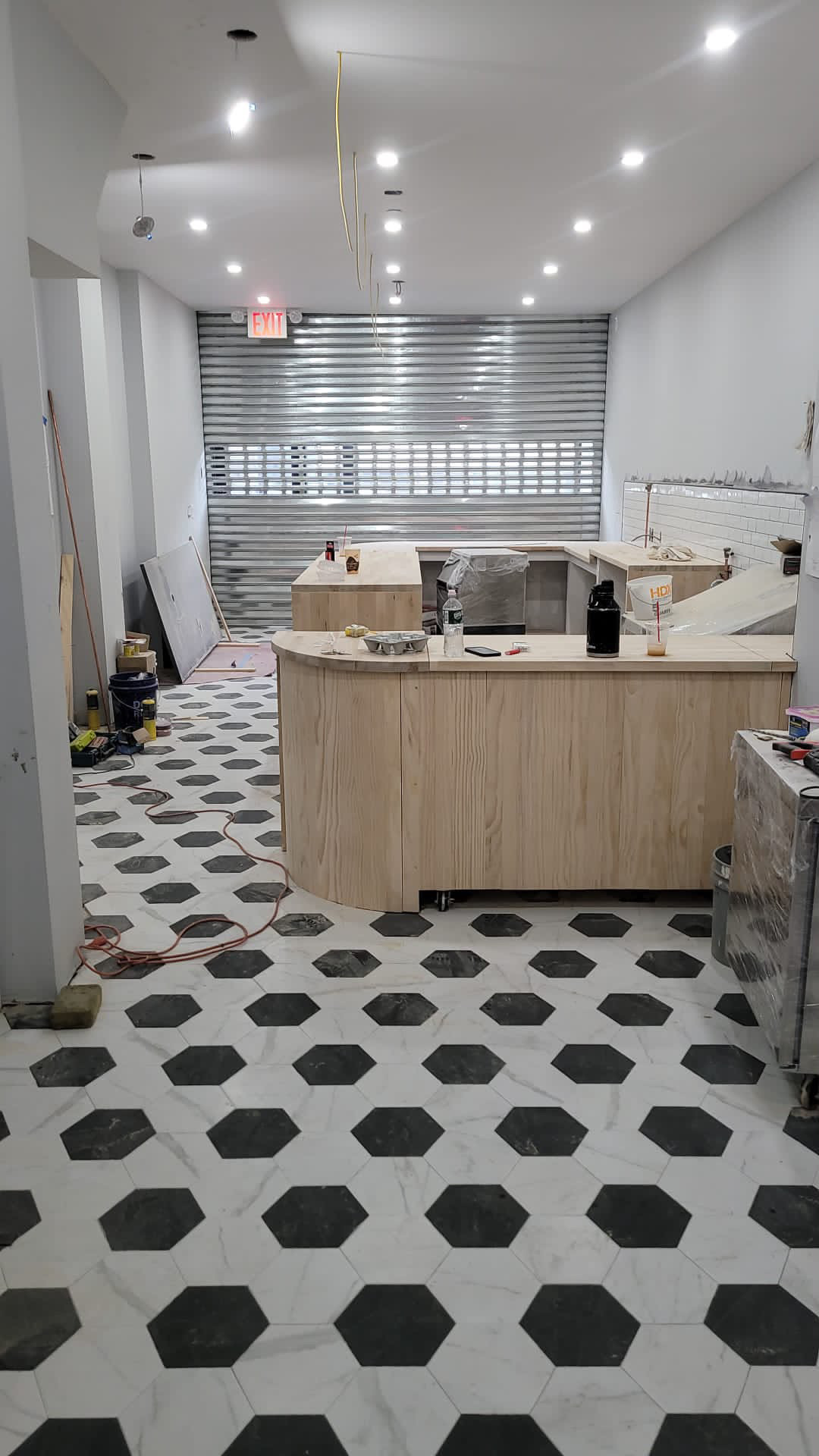 Construction in progress: custom wood counter being built, hex tile floor partially installed, subway tile on back wall