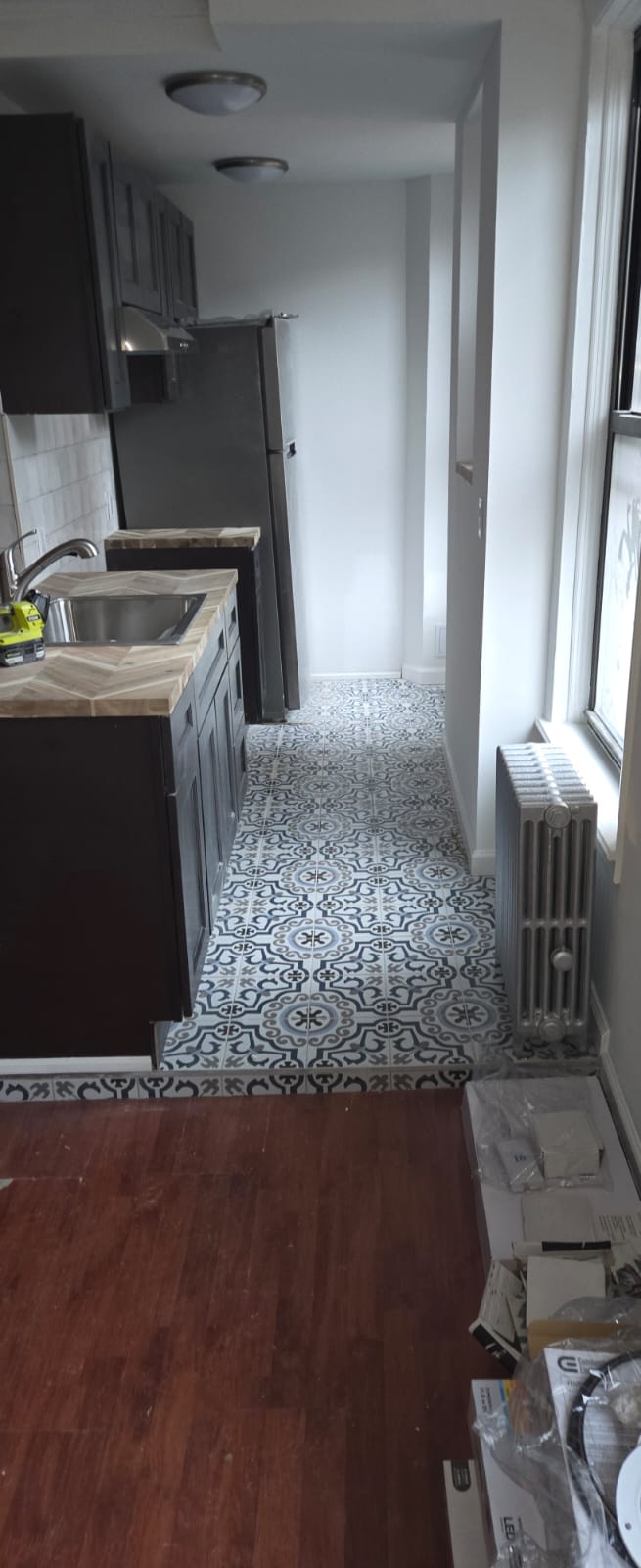 Completed kitchen with dark cabinetry, stone countertops and patterned tile floor